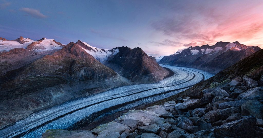 A glacier in a mountain range during sunset.